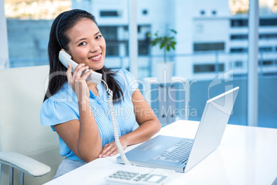 Smiling businesswoman using landline