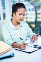 Smiling young businesswoman writing notes