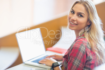 Smiling female student using laptop