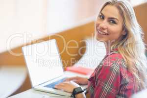 Smiling female student using laptop