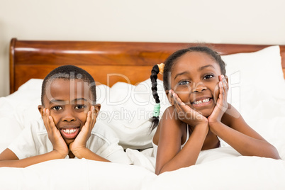 Portrait of happy siblings in bed