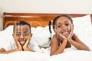 Portrait of happy siblings in bed