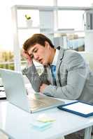 Tired asian businessman looking at his laptop