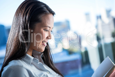 Smiling businesswoman reading book