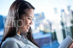 Smiling businesswoman reading book