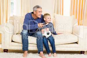 Father and son watching football match on tv