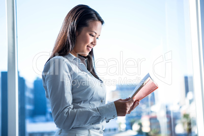 Smiling businesswoman reading book