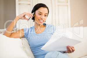 Smiling brunette on phone call holding sheets