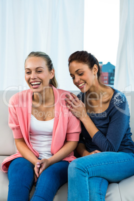 Happy friends laughing on sofa