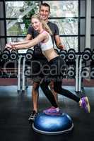 Fit woman with trainer exercising with bosu