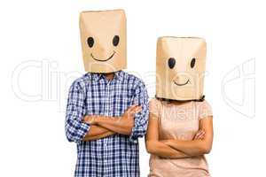 Couple with arms crossed wearing smiley paper bags