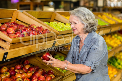 Smiling senior woman picking apple