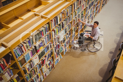 Student in wheelchair picking a book from shelf