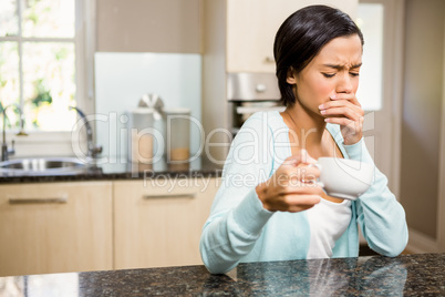 Frowning woman with toothache holding cup