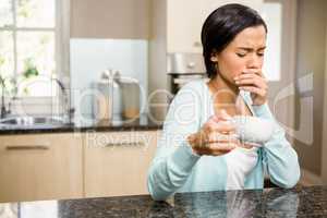 Frowning woman with toothache holding cup