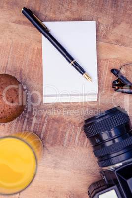 Cup cake and drink with notepad by camera on table