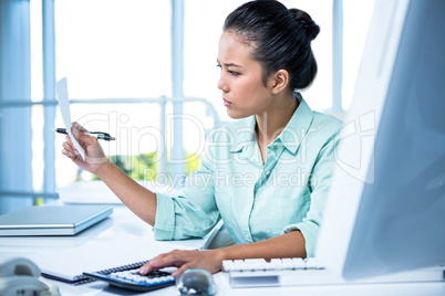 Smiling young businesswoman calculating bills