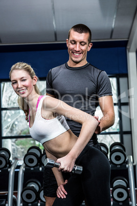 Fit woman doing dumbbells exercise with trainer