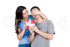 Happy woman covering boyfriend eyes while gifting