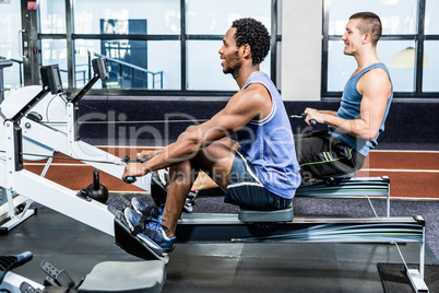 Muscular men using rowing machine