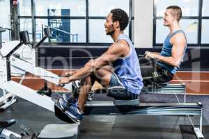 Muscular men using rowing machine