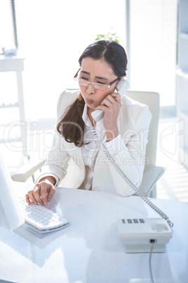 Anxious businesswoman using landline