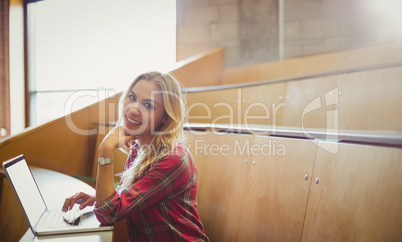 Smiling female student using laptop