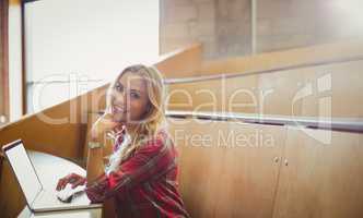 Smiling female student using laptop