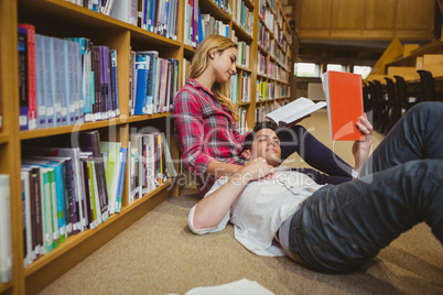 Student reading book while lying on his classmate