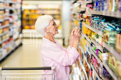 Senior woman taking a picture of product on shelf