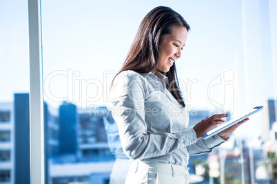 Smiling businesswoman using tablet near the window in office