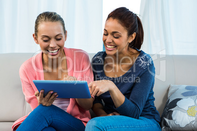 Friends using tablet on sofa