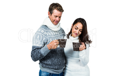 Festive couple smiling and holding mugs