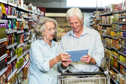 Senior couple using tablet at the supermarket
