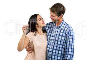 Cheerful couple embracing while holding keys