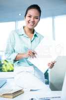 Smiling businesswoman sitting on her desk