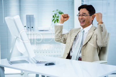Smiling businessman with arms raised