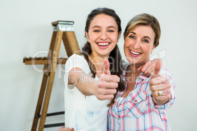Smiling mother and daughter with thumbs up