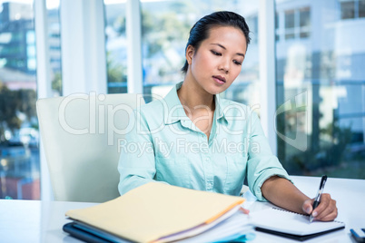 Smiling young businesswoman writing notes