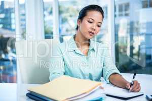 Smiling young businesswoman writing notes