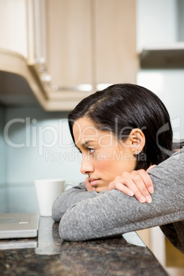 Thoughtful brunette looking at laptop