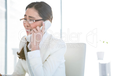 Anxious businesswoman using landline