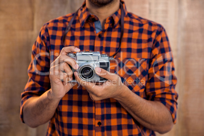 Mid section of businessman holding camera against wall