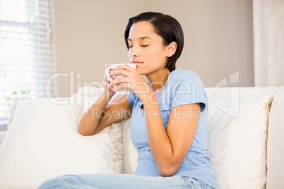 Relaxed brunette drinking by white cup