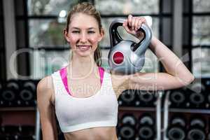 Smiling fit woman lifting kettlebell