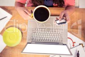 Cropped image of businesswoman using phone while holding coffee