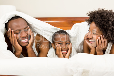 Happy family smiling under blanket