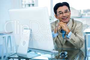 Smiling asian businessman working on computer