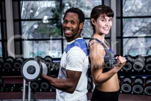 Fit couple lifting dumbbells back to back