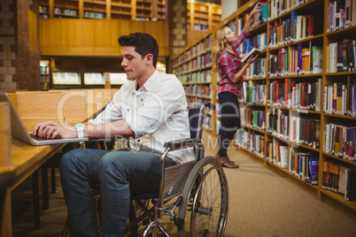 Student in wheelchair typing on his laptop while woman searching